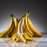 Stehende, halb geschälte Banane vor mehreren stehenden Bananen