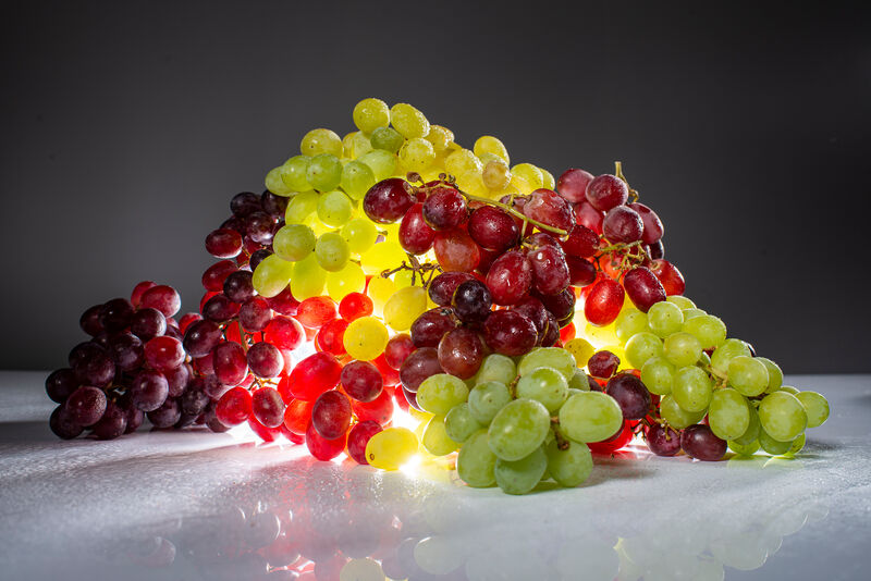 grüne Weintraube vor roten und grünen Weintrauben liegend