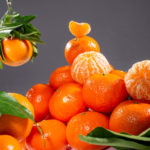 geschälte Clementine auf ungeschälten Clementinen liegend