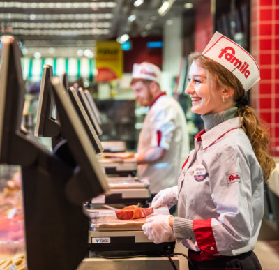 Fleischerei-Auszubildende wiegt hinter dem Tresen ein Stück Fleisch